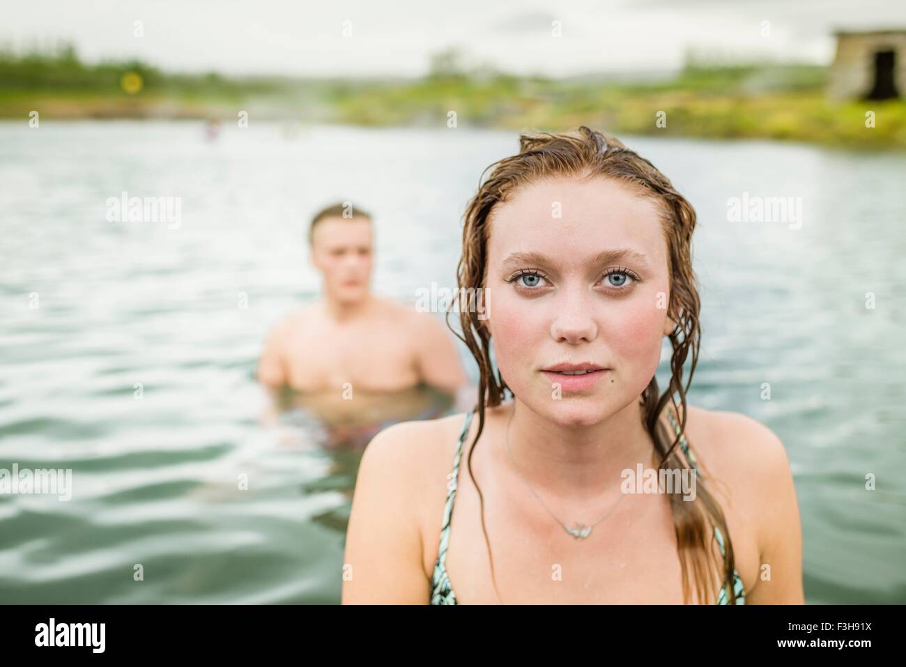 Portrait of young woman standing in front of boyfriend in Secret Lagoon hot spring (Gamla Laugin), Fludir, Iceland Stock Photo