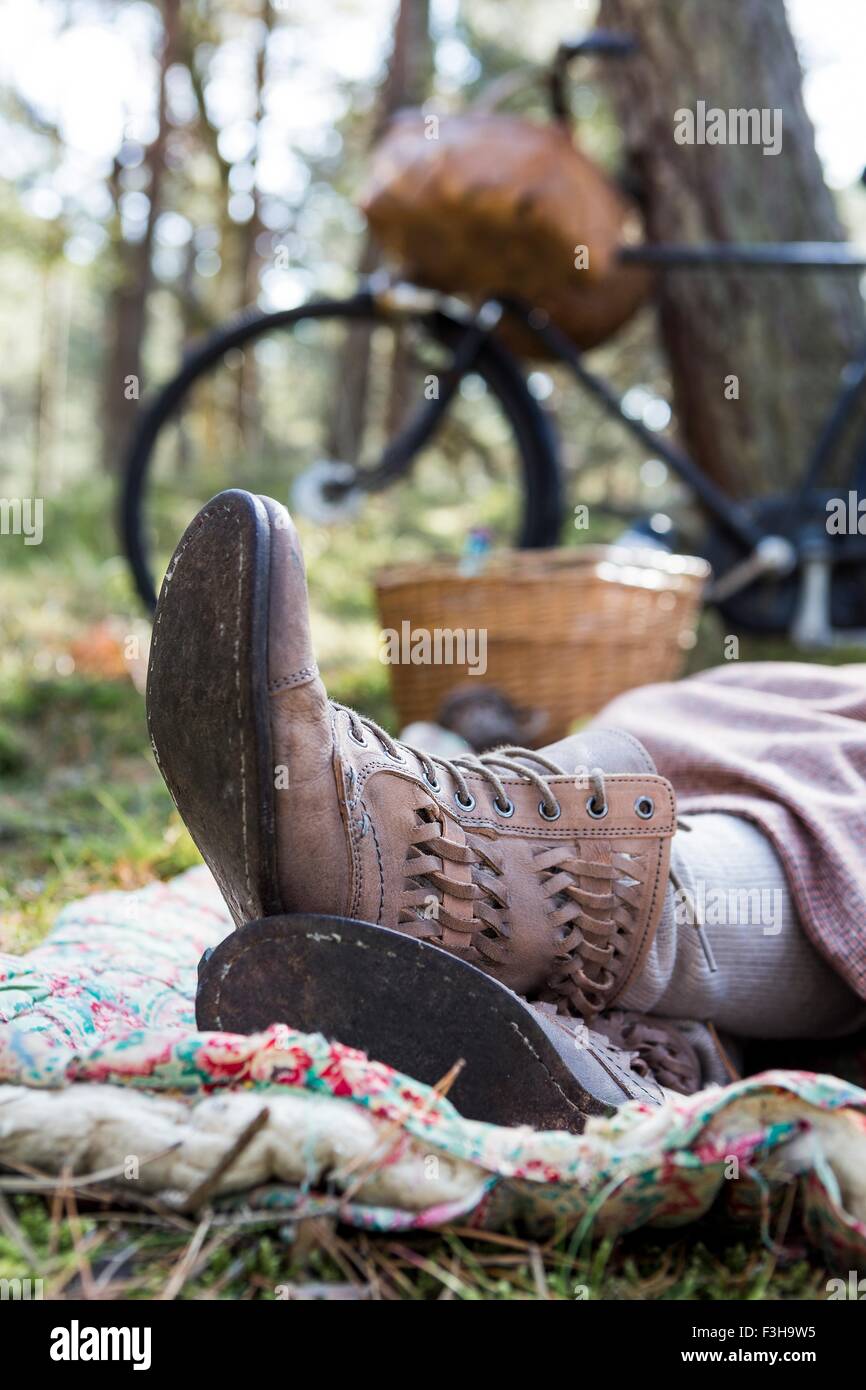 Feet and ankle boots of female forager resting on blanket in forest Stock Photo