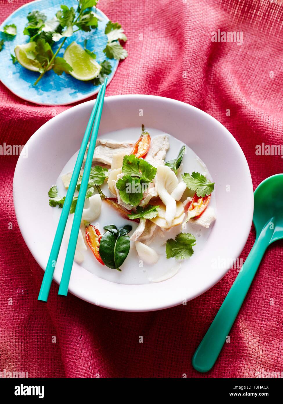 Overhead view of tom kha gai in bowl with chopsticks and soup spoon Stock Photo