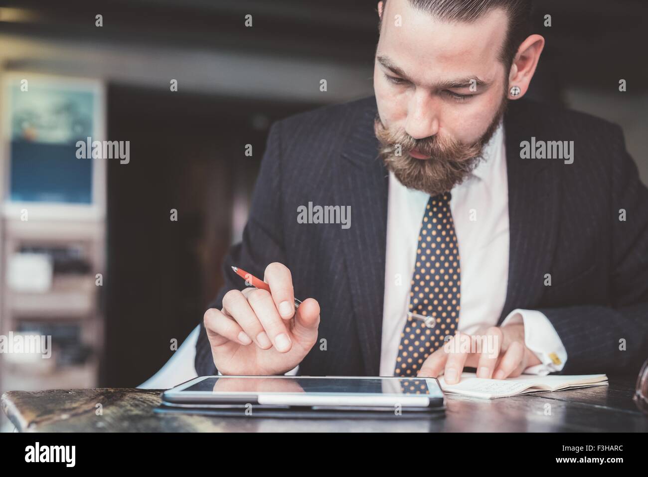 Businessman making diary notes from digital tablet at cafe table Stock Photo