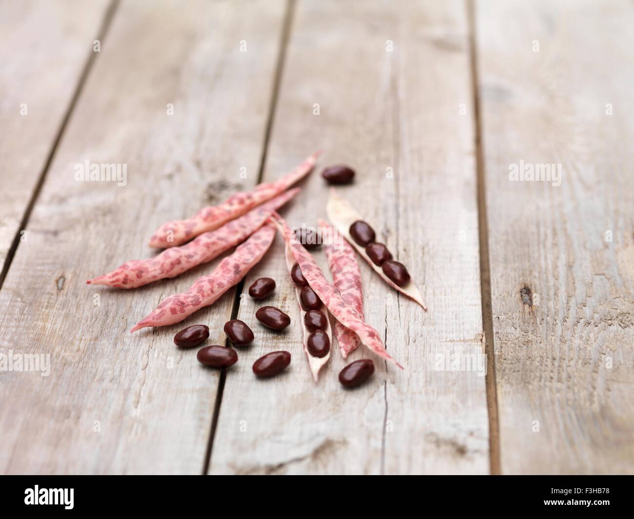 Still life of red kidney beans and pods on wooden table Stock Photo