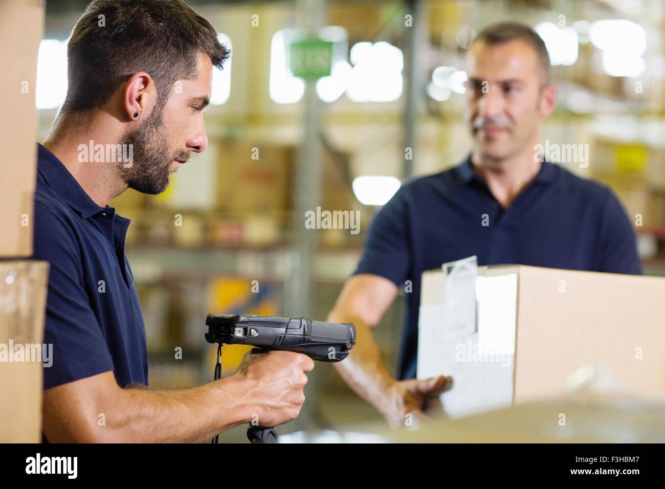 Two warehouse workers using barcode scanner in distribution warehouse