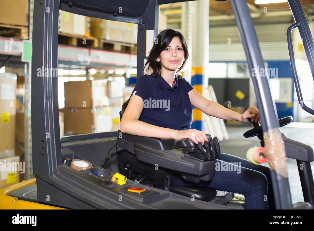 Portrait of female forklift truck driver working in distribution warehouse Stock Photo