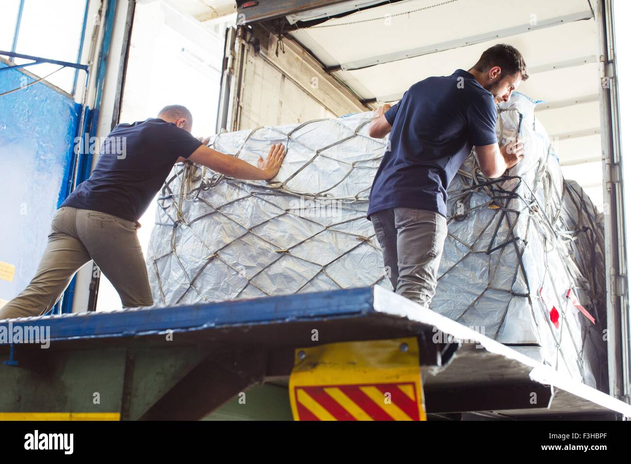 Workers pushing freight into air freight container Stock Photo
