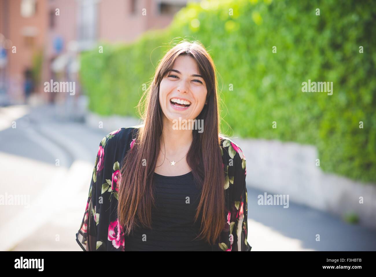Portrait of young woman with long brown hair laughing Stock Photo