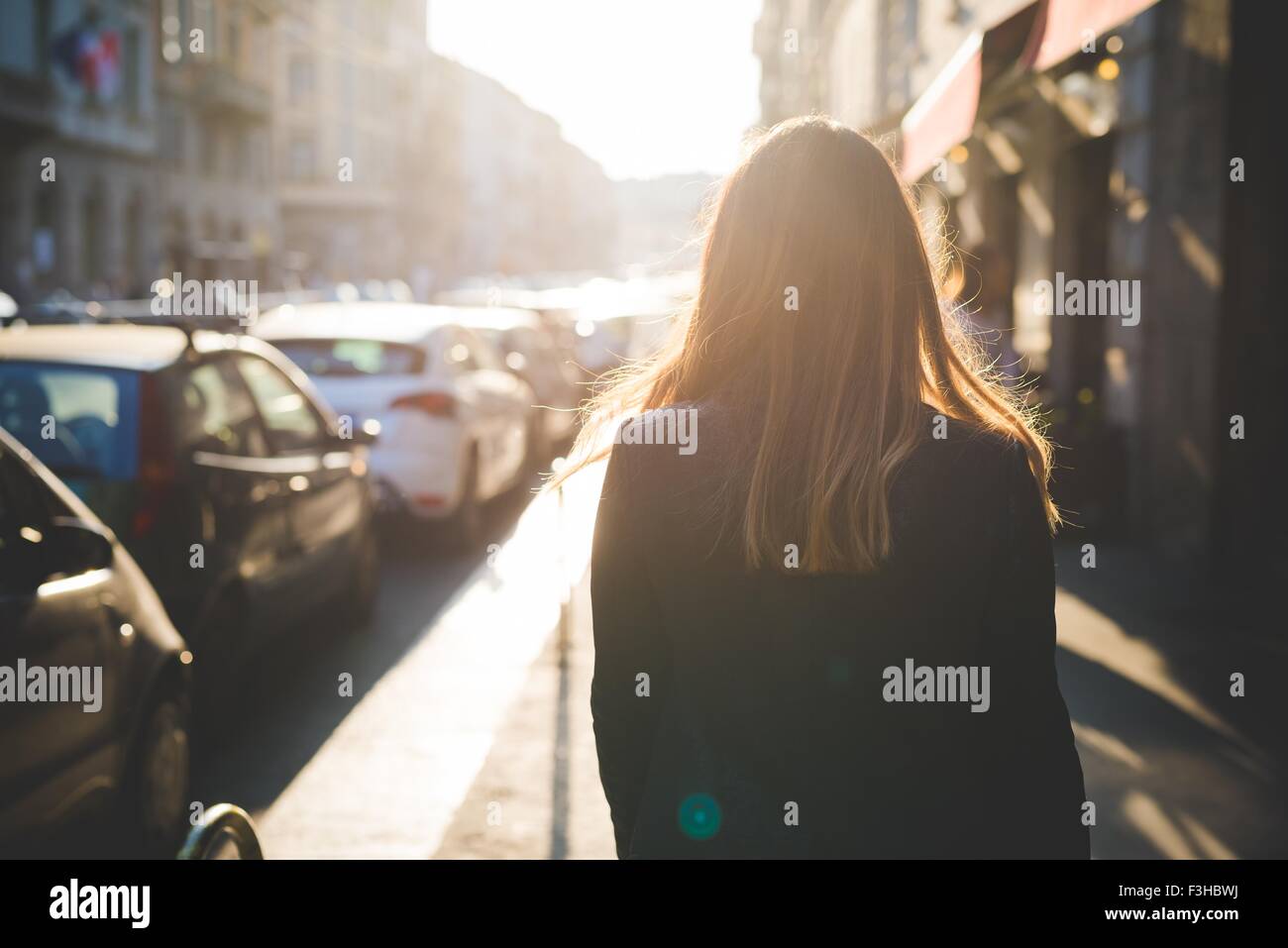 Rear view of young woman strolling on city street Stock Photo - Alamy