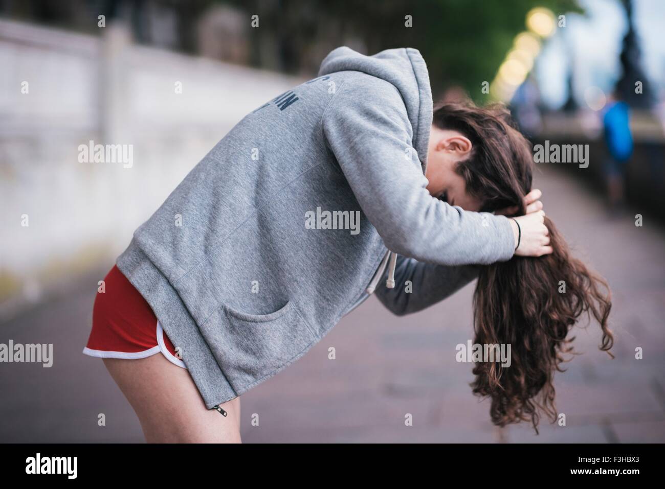 Young Female Runner Tying Up Long Hair On Riverside Stock Photo
