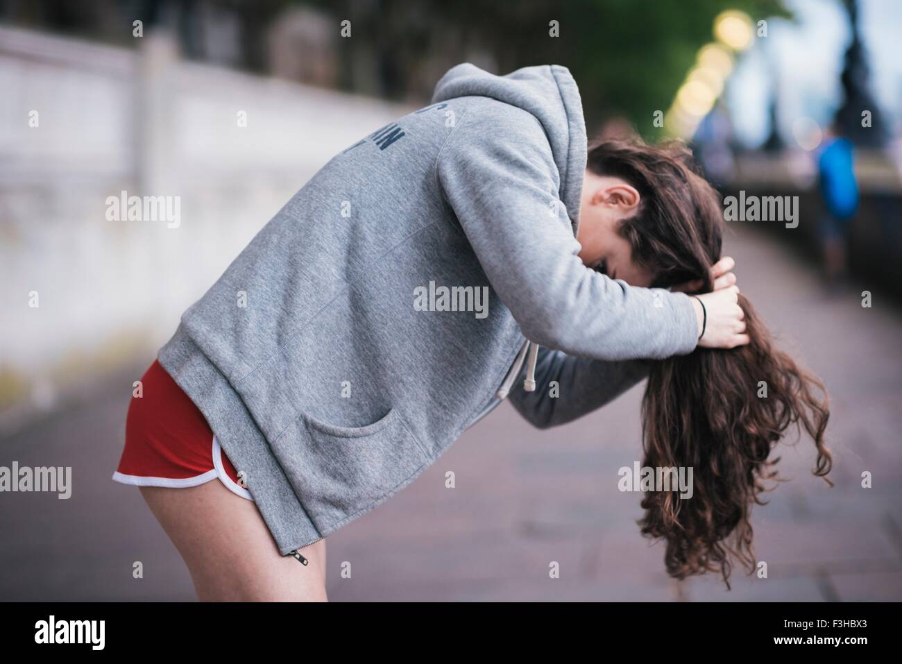 Young female runner tying up long hair on riverside Stock Photo