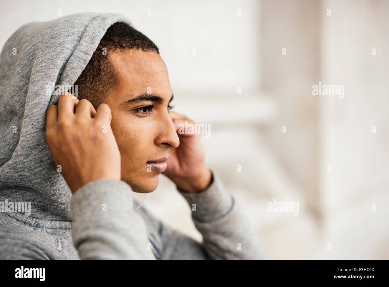 Male runner wearing grey hoody putting in earphones Stock Photo