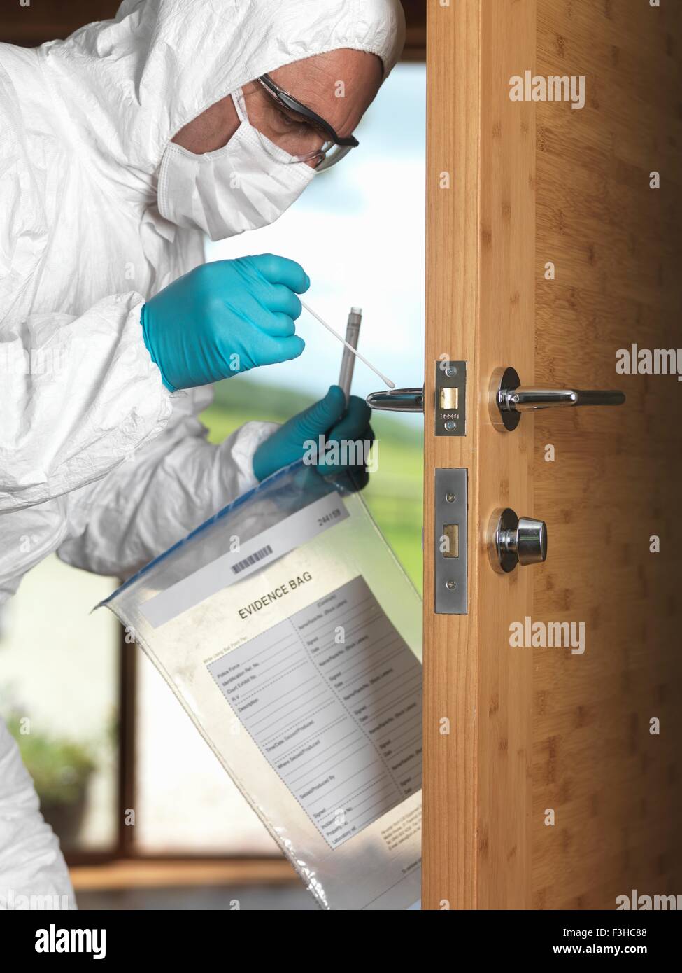 Forensic officer taking DNA swab off door handle Stock Photo