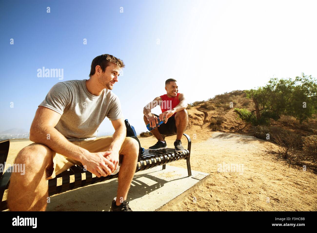 Two male friends, sitting on bench, on cliff top, looking at view Stock ...