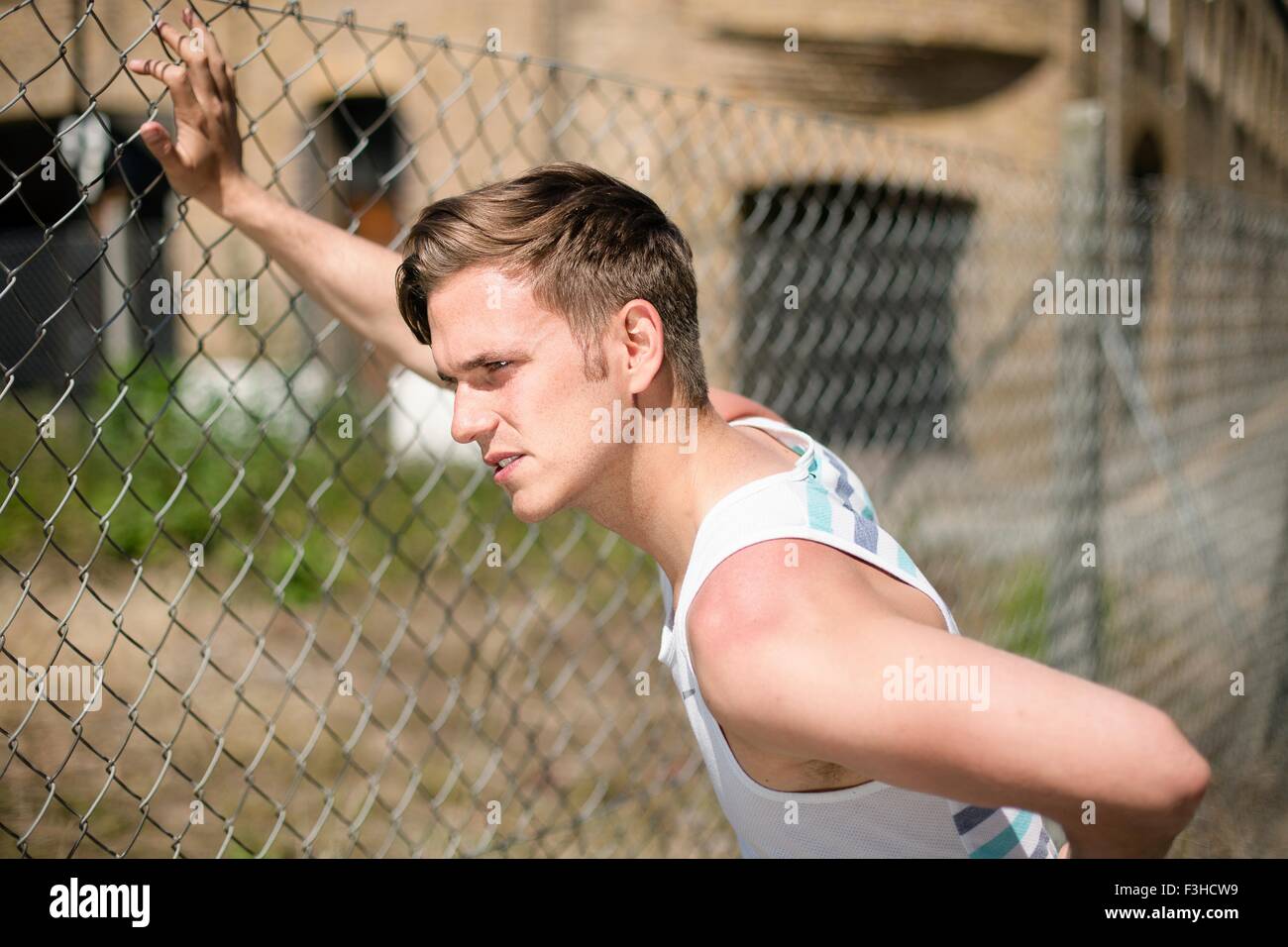 Runner stretching against wire fence, Wapping, London Stock Photo