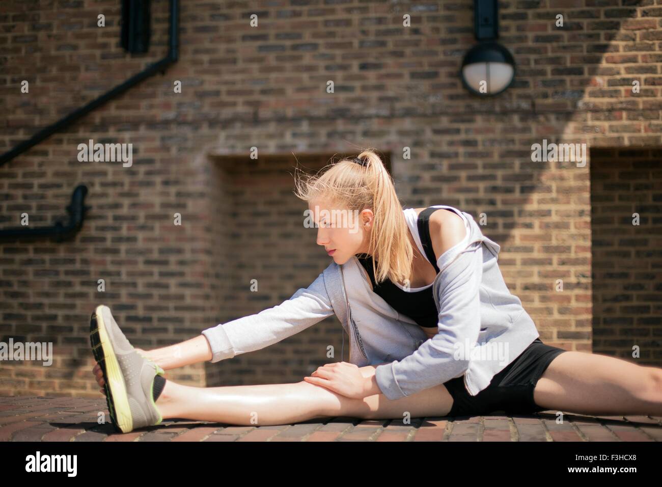 Runner stretching on walkway, Wapping, London Stock Photo