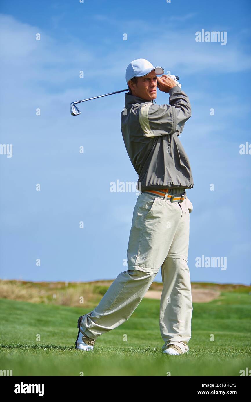 Full length front view of golfer holding golf club taking golf swing