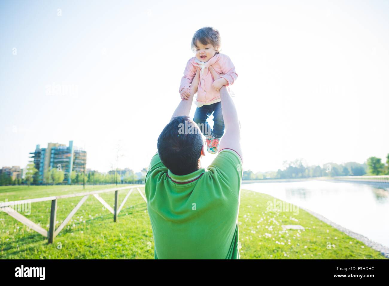 Mid adult man lifting up toddler daughter in park Stock Photo