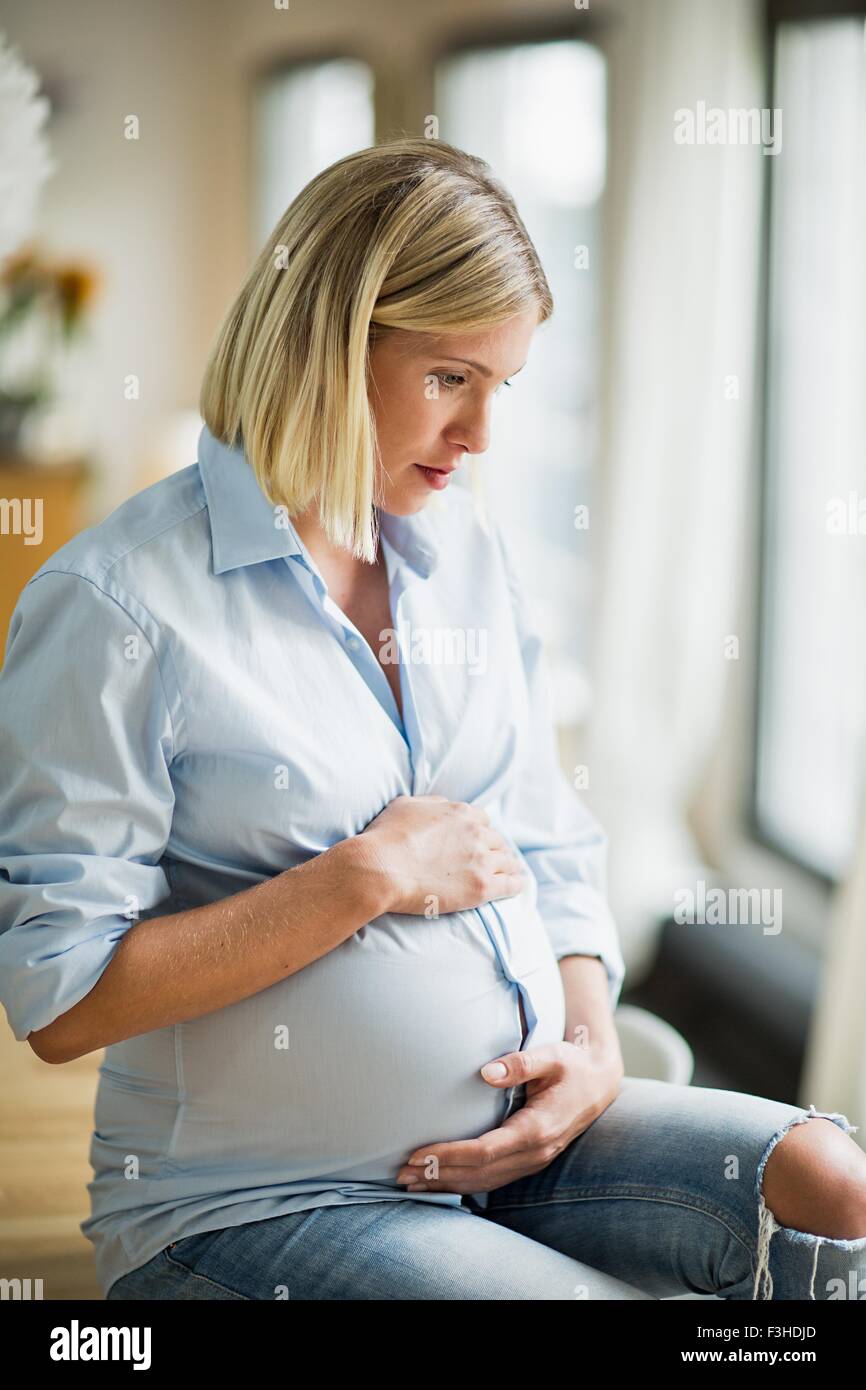 Full term pregnancy young woman sitting on table Stock Photo