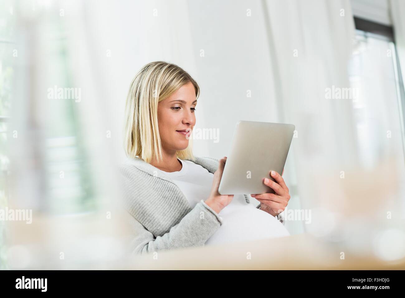 Full term pregnancy young woman using touchscreen on digital tablet Stock Photo