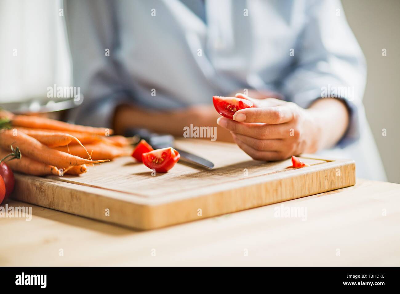 Cropped shot of full term pregnancy young woman slicing tomato in kitchen Stock Photo