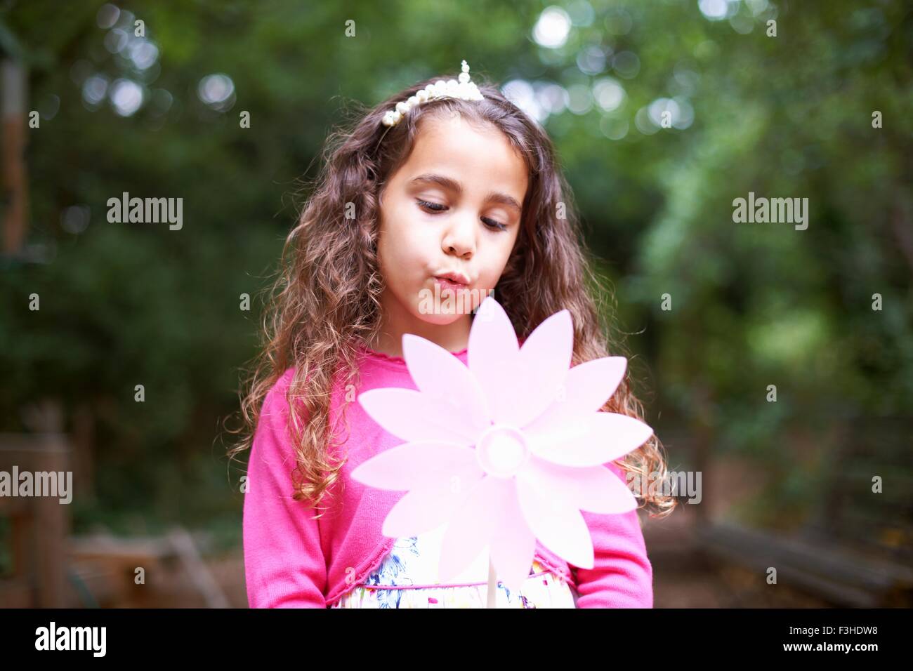 Girl blowing flower pinwheel at garden birthday party Stock Photo