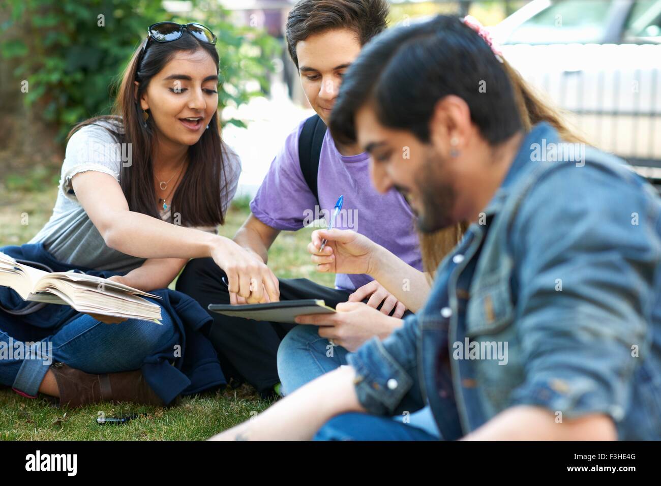 Male and female students sitting chatting and working on college campus Stock Photo