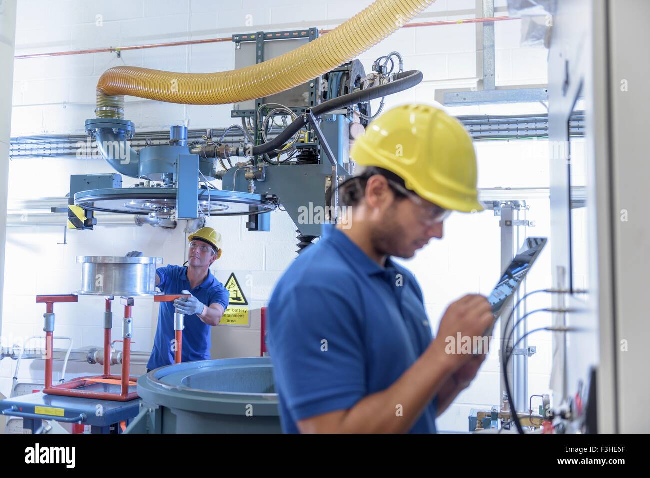 Workers operating environmental testing equipment with digital tablet in electronics factory Stock Photo
