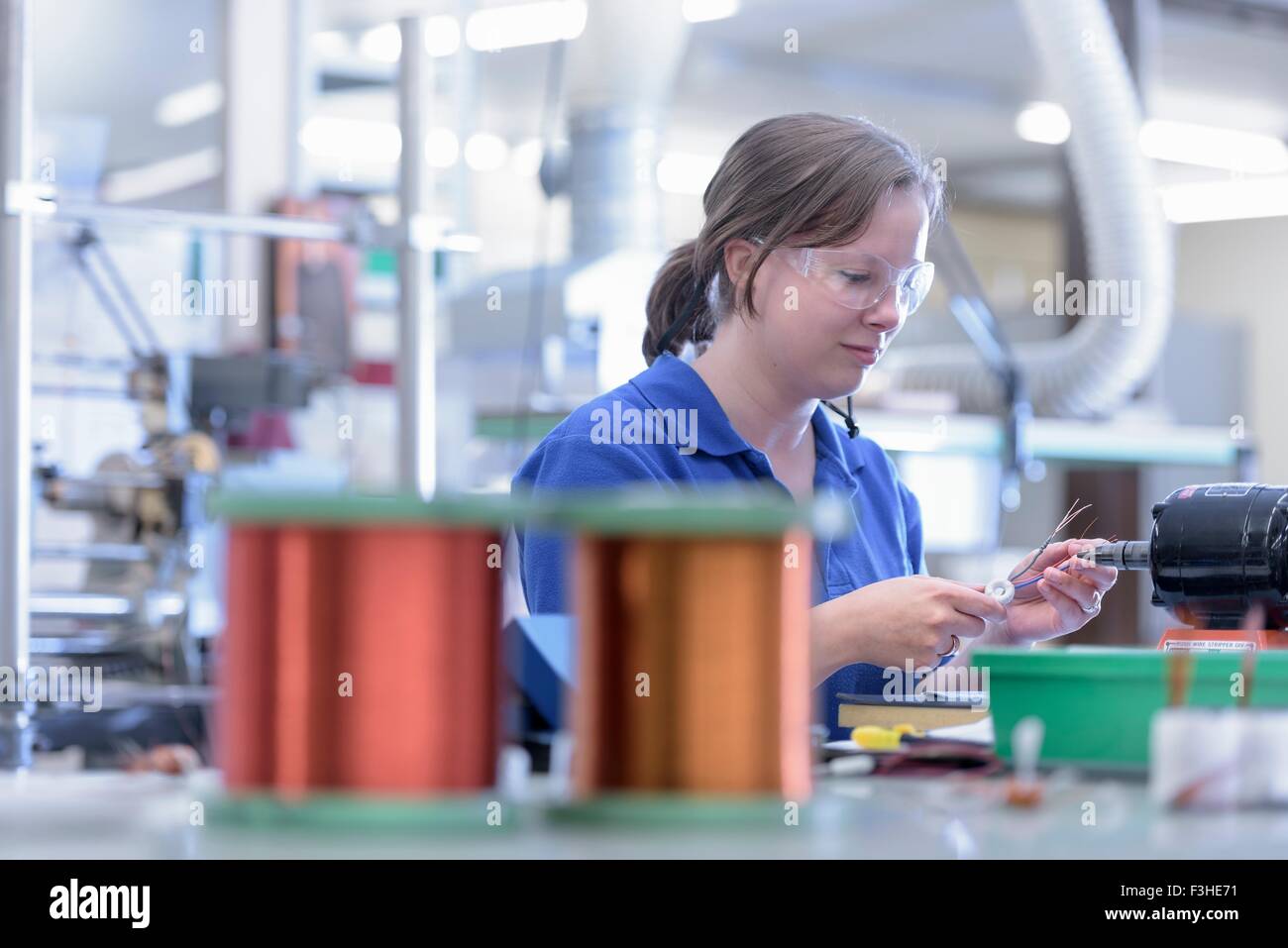 Female worker assembling electromagnetic coils in electronics factory Stock Photo