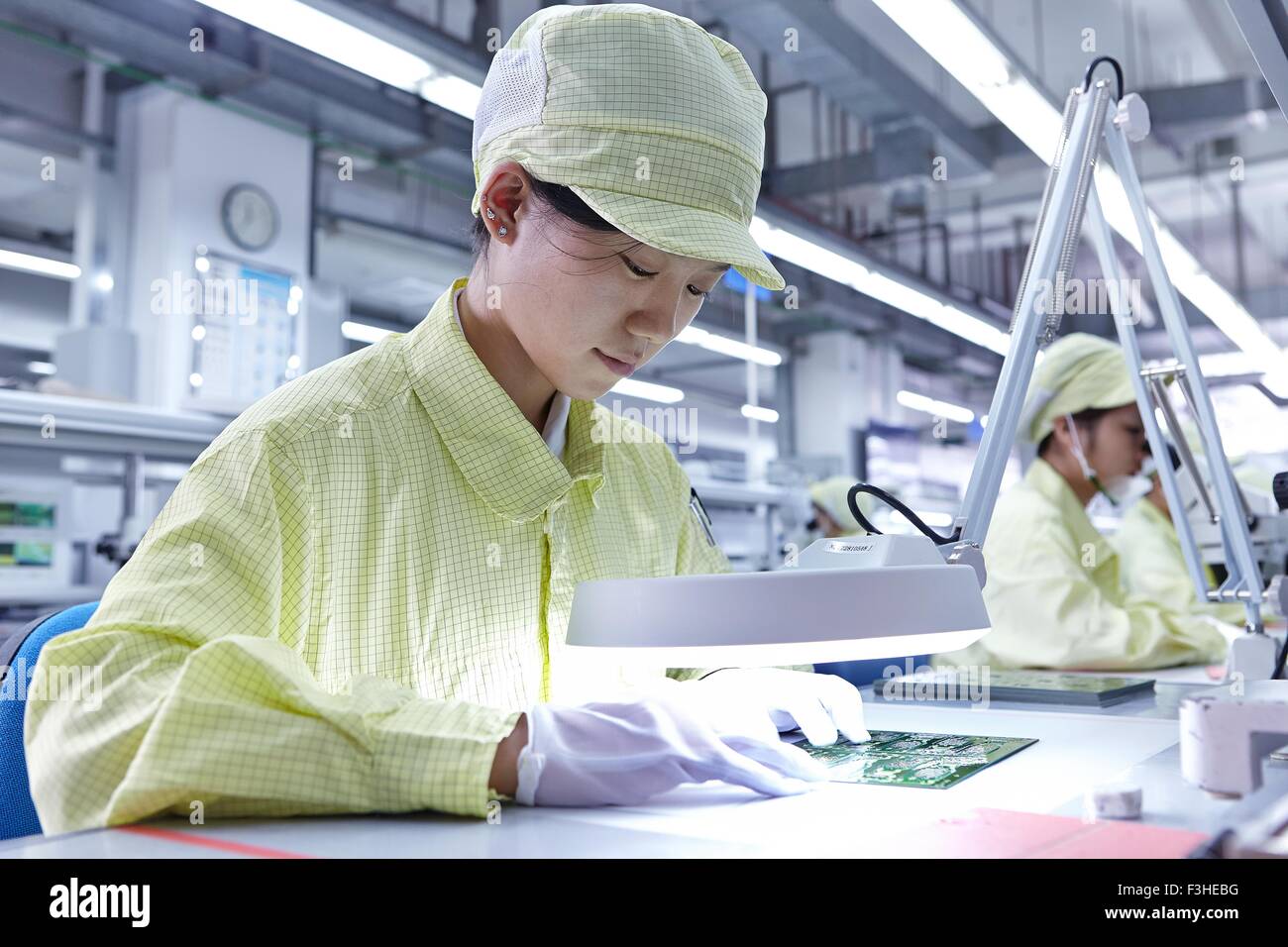 Young woman working quality check station factory producing flexible electronic circuit boards Stock Photo