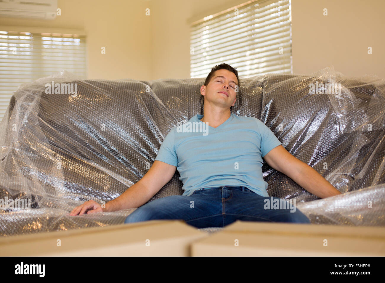 tired young man napping on couch in new house during moving Stock Photo