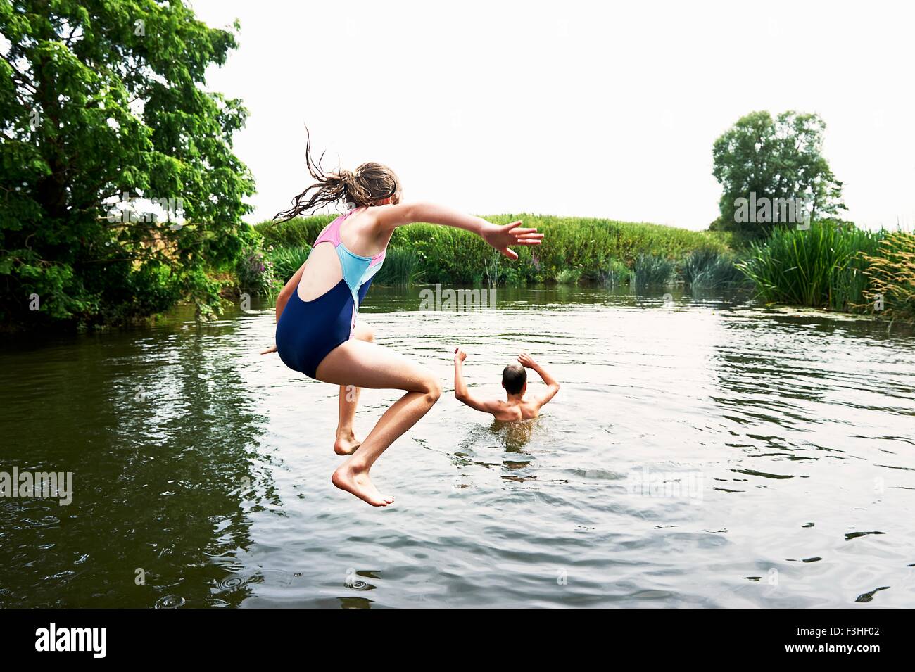 Teenage boy and sister jumping into lake Stock Photo