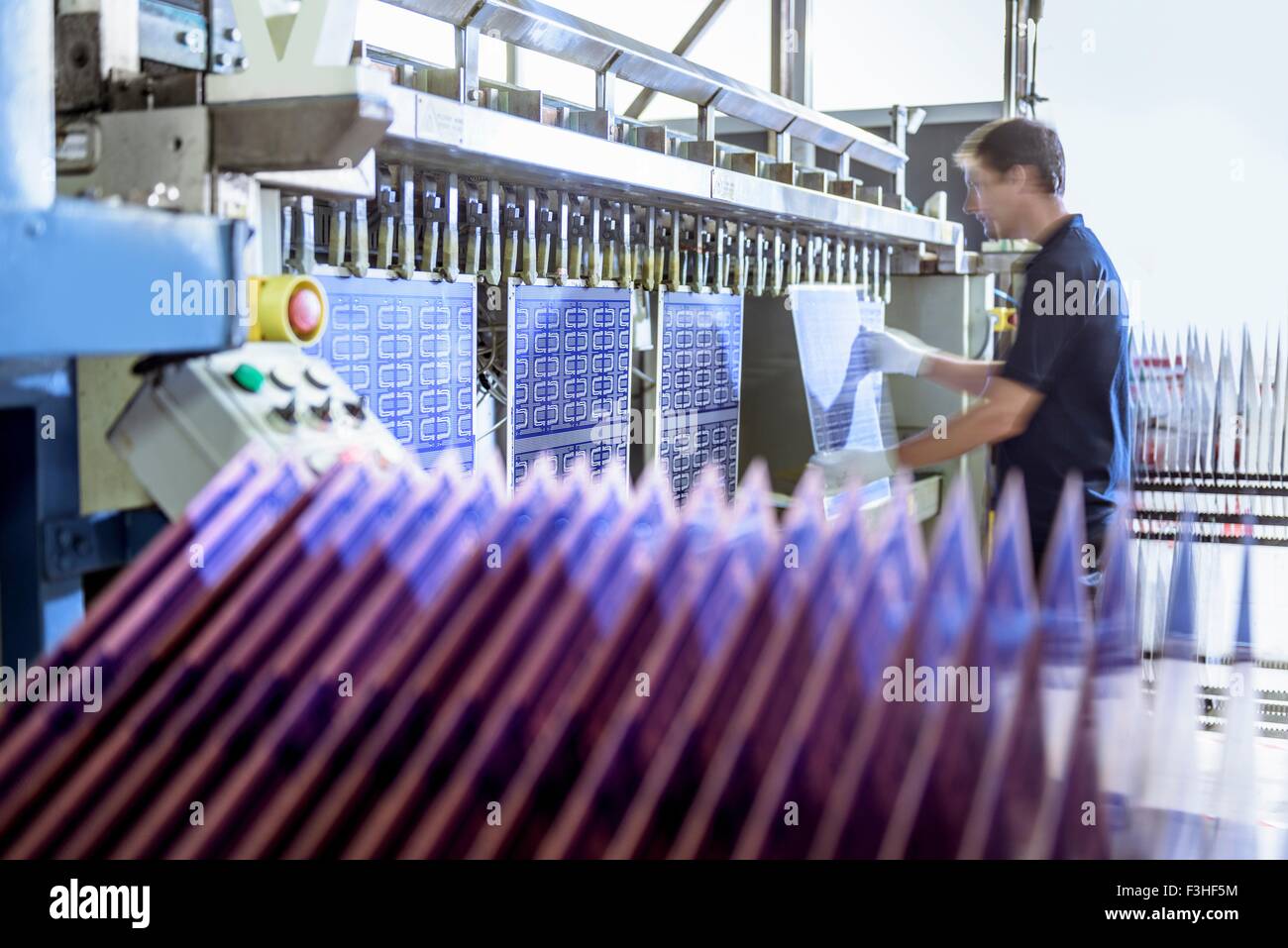 Worker loading circuit boards into processing machine in circuit board factory Stock Photo