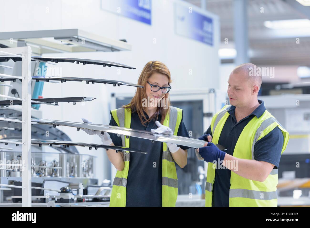 Workers checking paint finish on automotive parts in spray paint factory Stock Photo