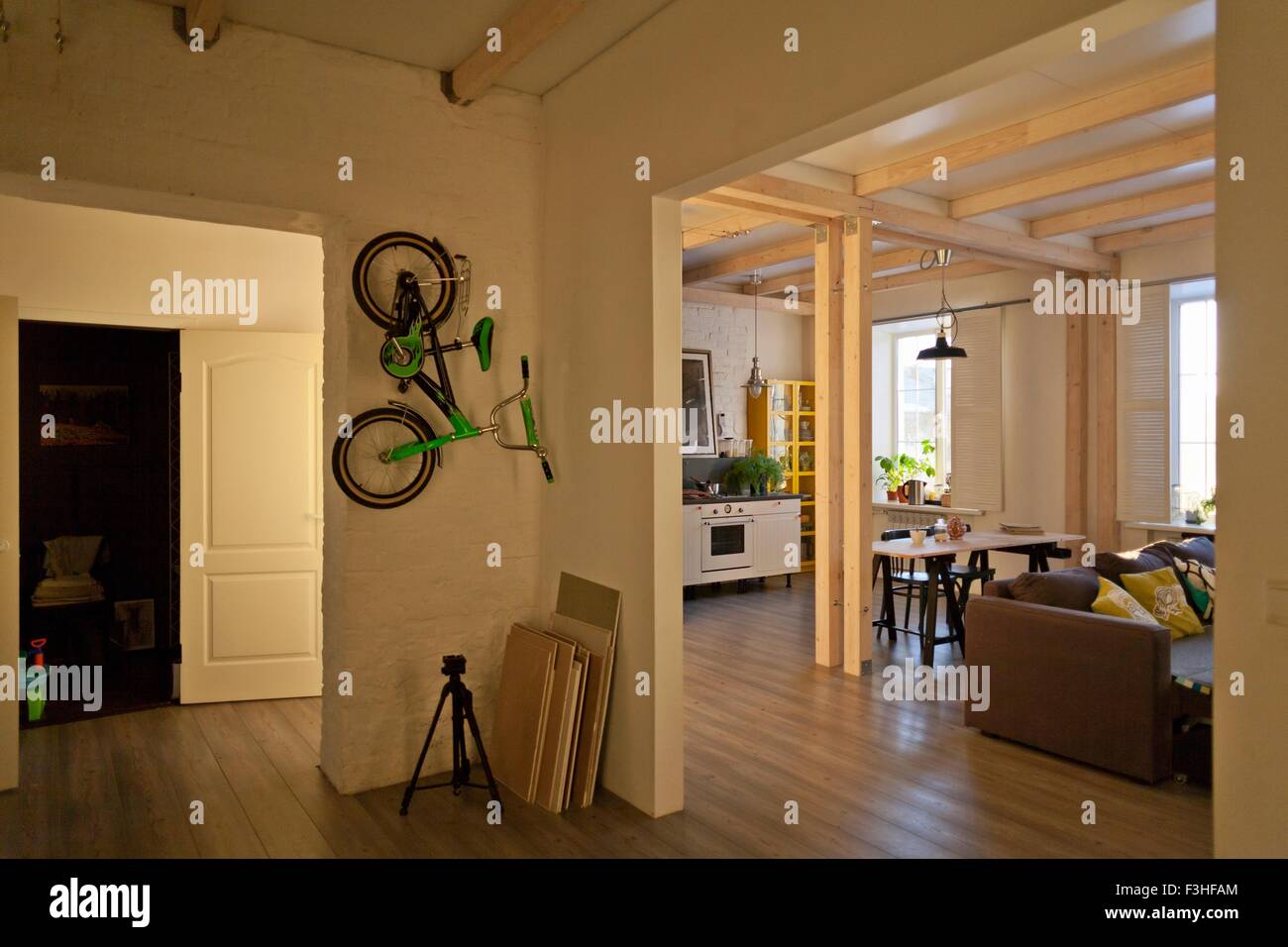View of storage room, kitchen, dining area, couch and bicycle on wall Stock Photo