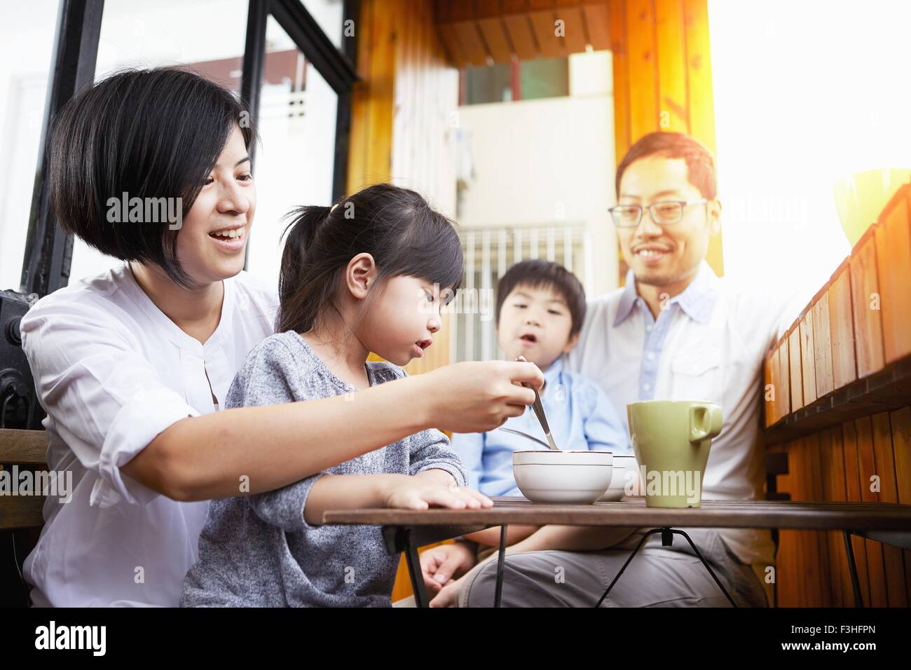 Young Chinese family having breakfast on the balcony in the sunshine together Stock Photo