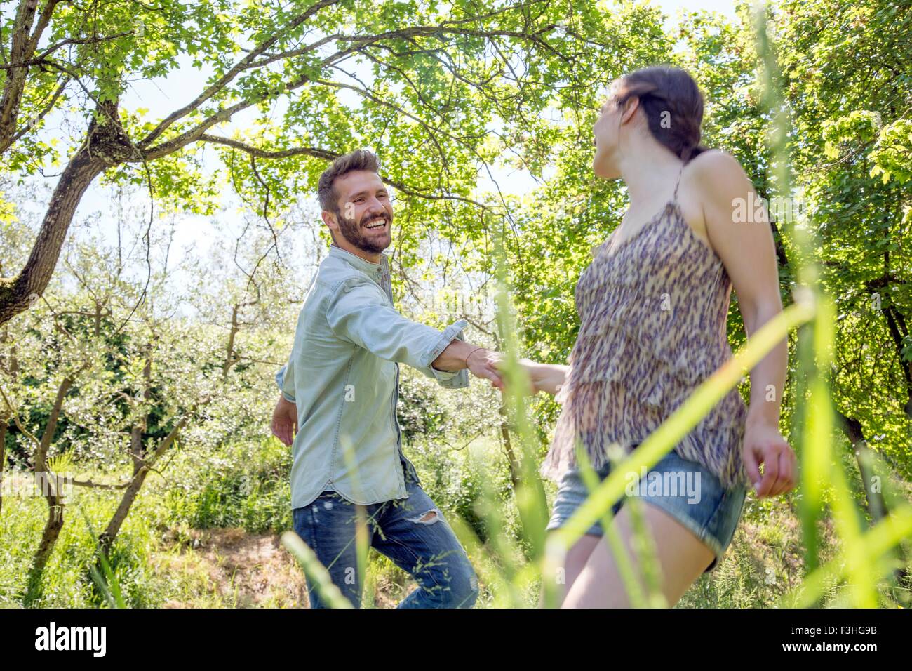 Young couple holding hands in forest fooling around smiling Stock Photo