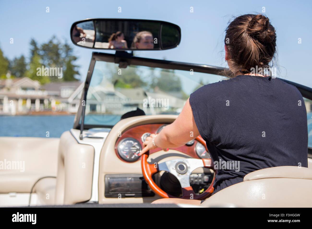 Rear view of young woman driving motor boat, Lake Oswego, Oregon, USA Stock Photo