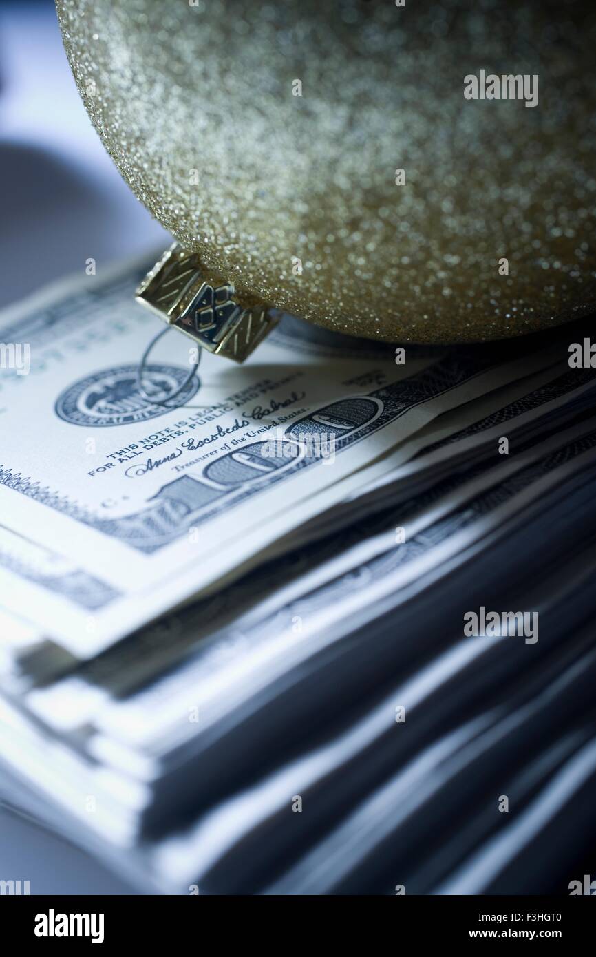 Sparkly christmas bauble on top of pile of 100 dollar bills Stock Photo