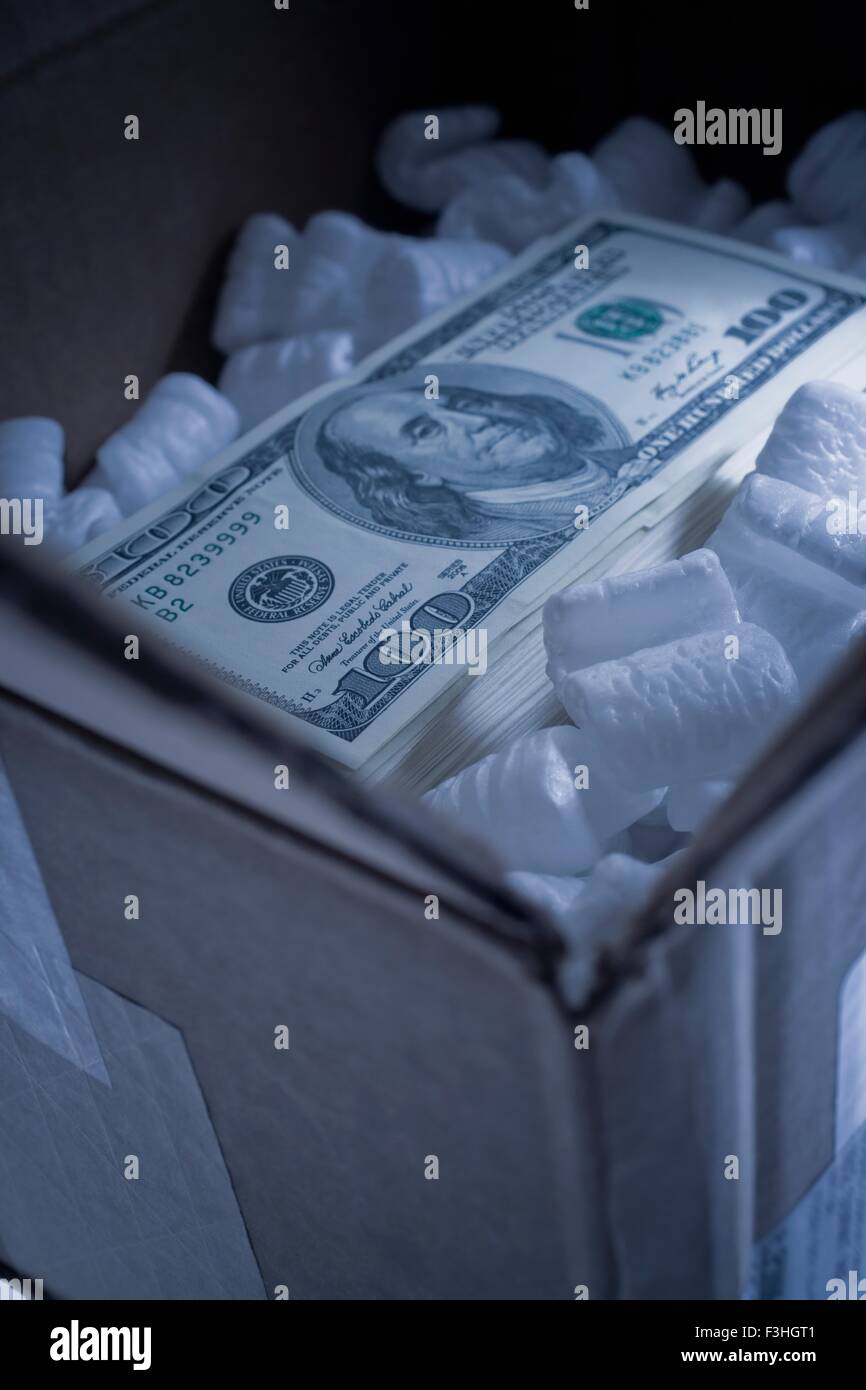 Stack of one hundred dollar bill in cardboard box with foam packing peanuts Stock Photo