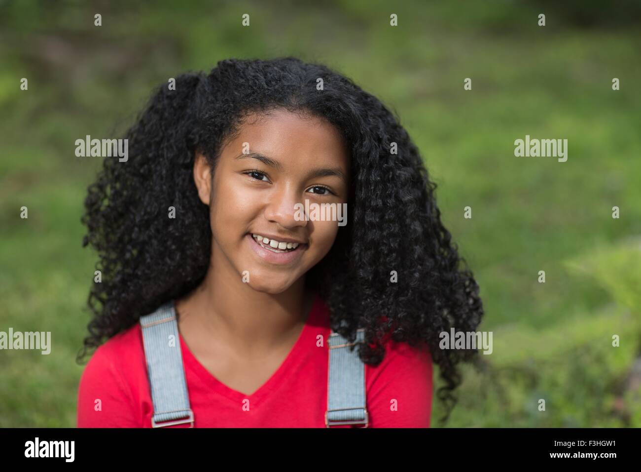 Portrait of girl with black curly hair looking at camera smiling Stock Photo