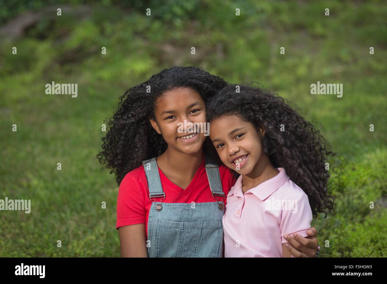 Portrait of girl with arm around her sister, looking at camera smiling Stock Photo