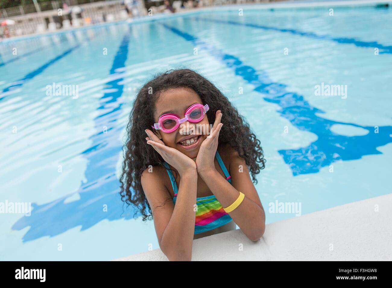 Portrait of girl in swimming pool wearing swimming goggles, looking at camera smiling Stock Photo