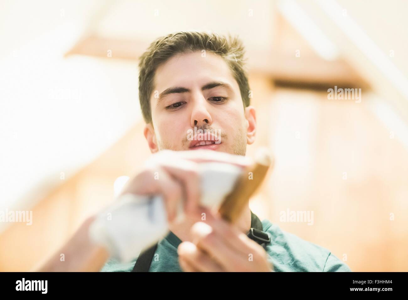 Low angle view of young man crafting wood object, looking down Stock Photo
