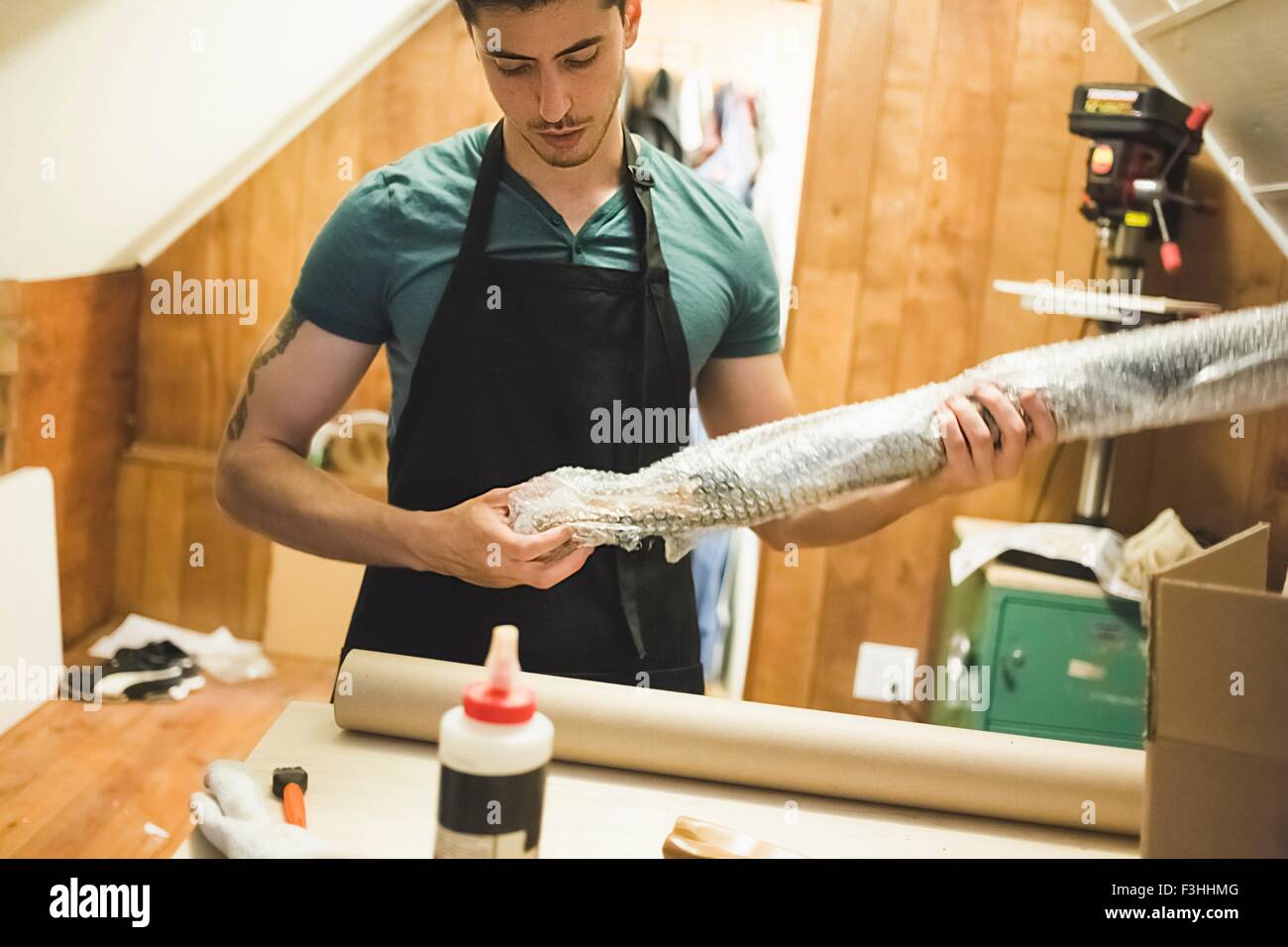 Young man using bubble wrap to prepare parcel for delivery Stock Photo