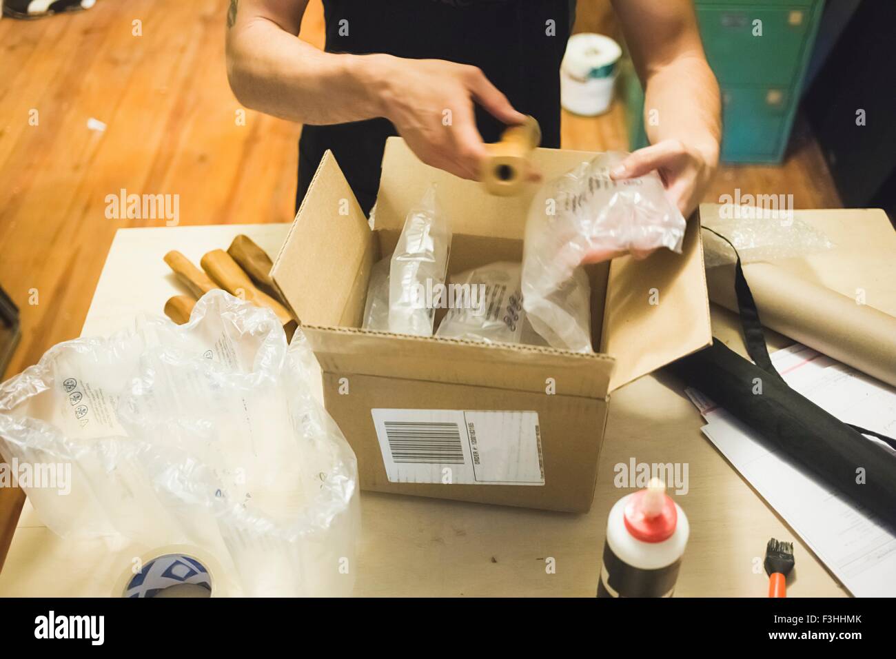 High angle view of young mans hands using bubble wrap to prepare parcel for delivery Stock Photo