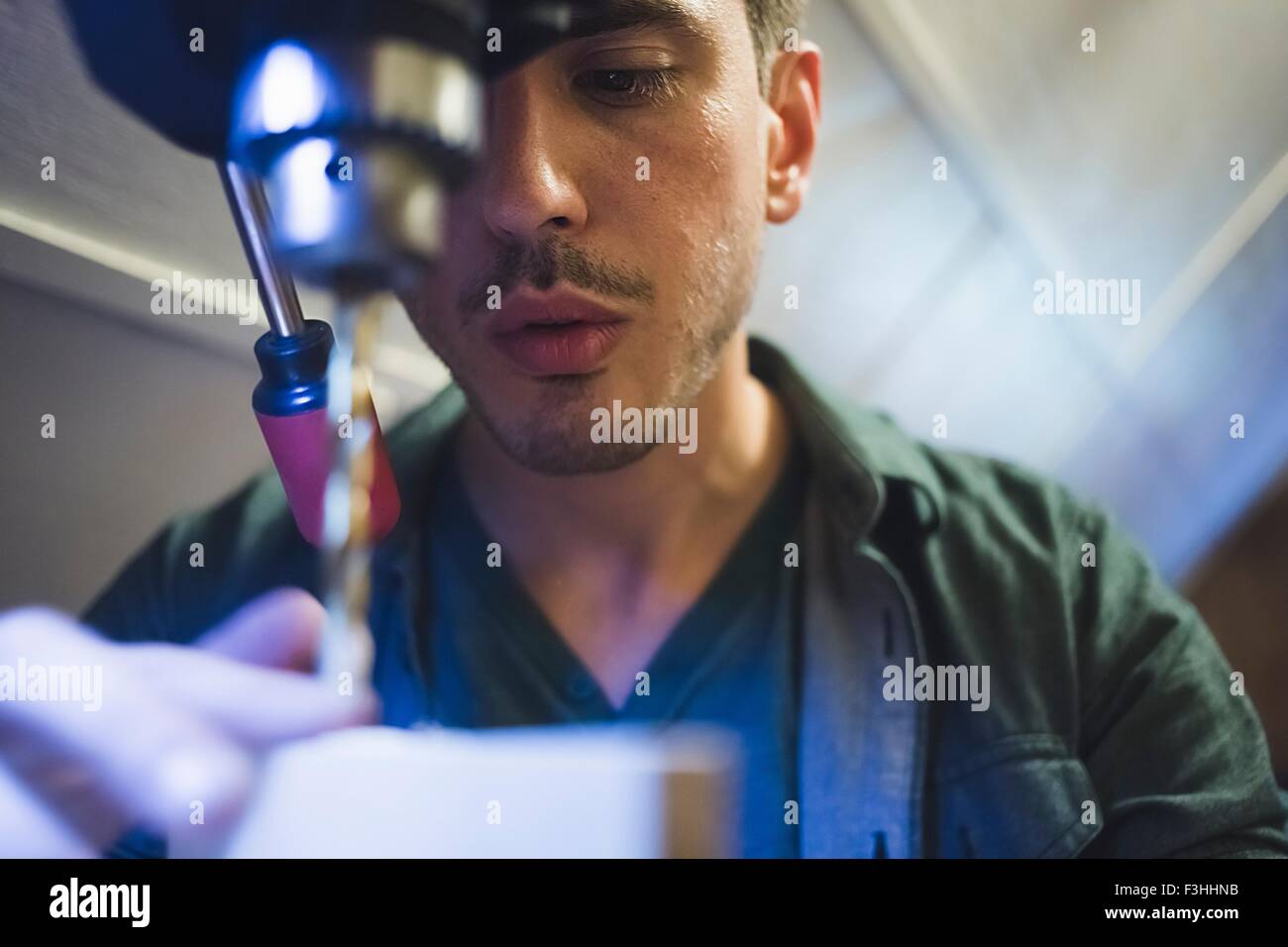 Low angle view of young man using tool, face partially obscured Stock Photo