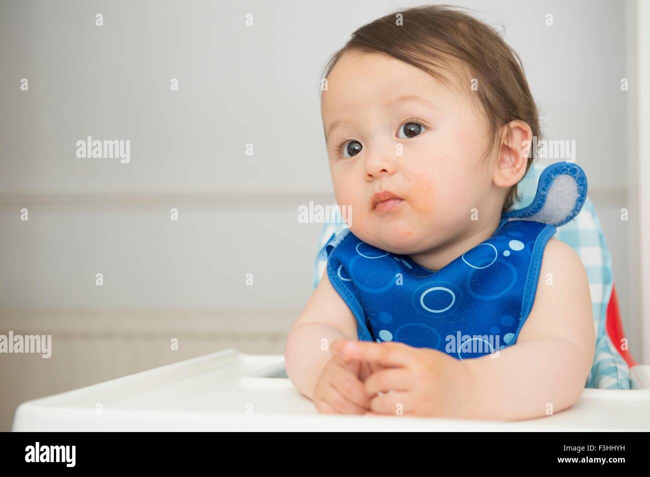 Baby boy watching from kitchen high chair Stock Photo Alamy