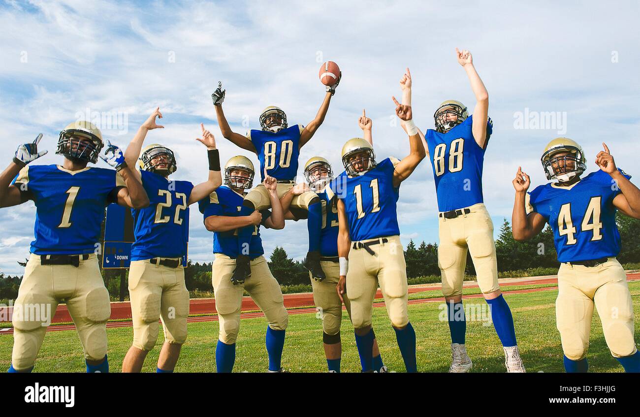 Teenage and young male American football team celebrating on soccer pitch Stock Photo