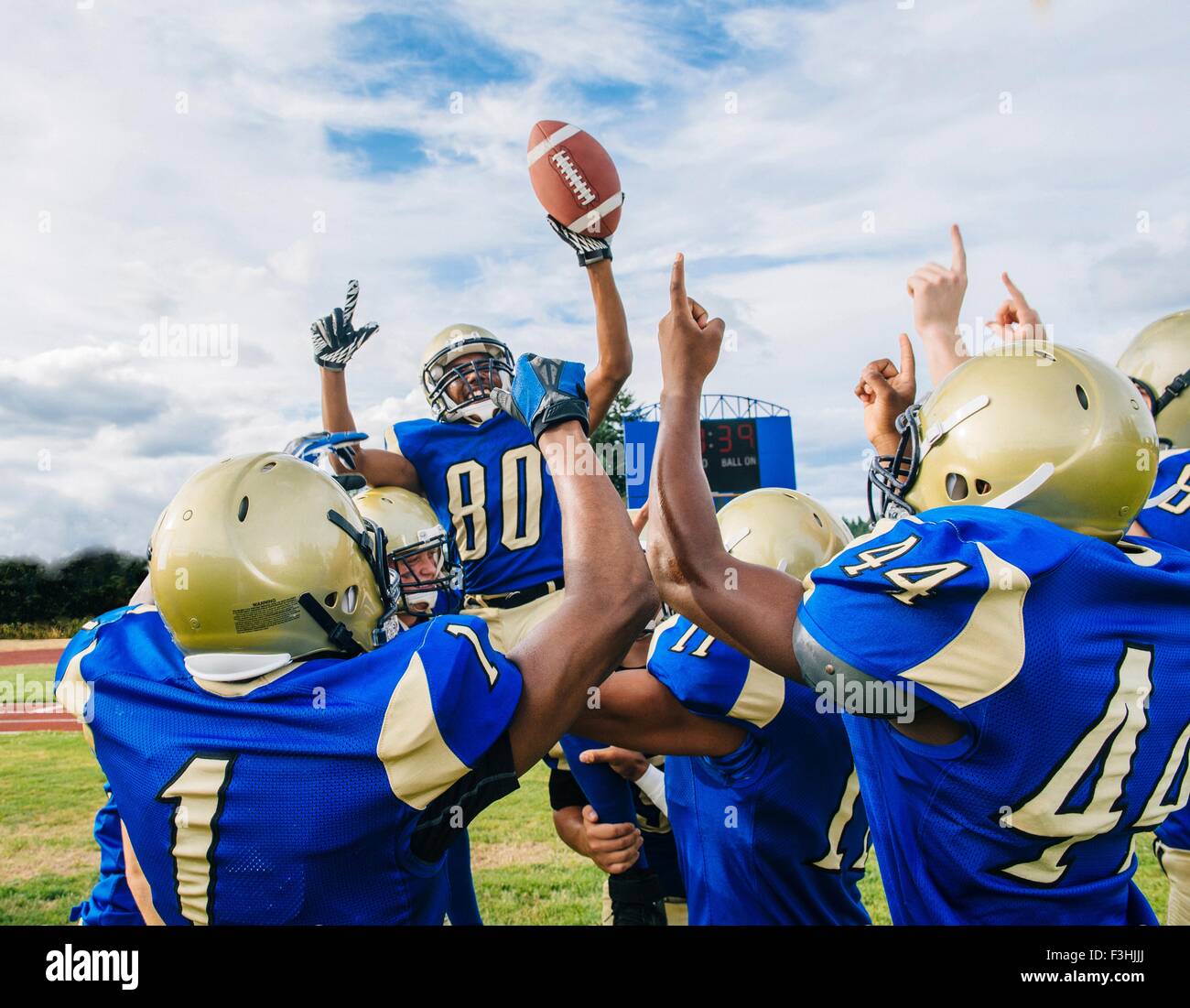Teenage and young male American football team celebrating victory on