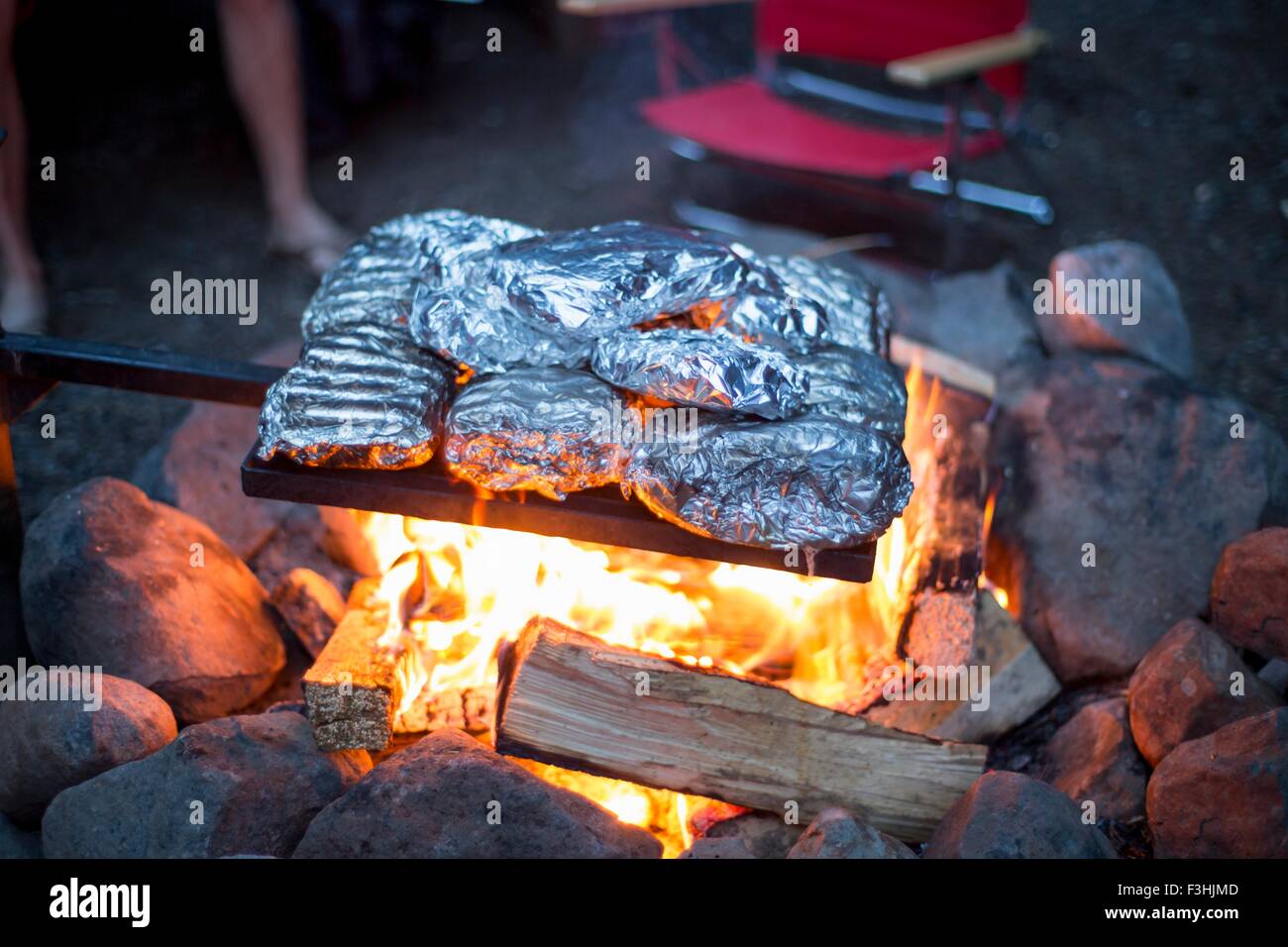 Food wrapped in tin foil cooking over campfire Stock Photo