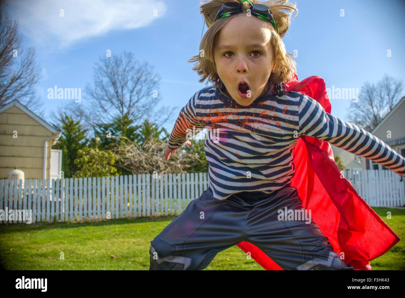 Boy with red cape pretending to fly Stock Photo