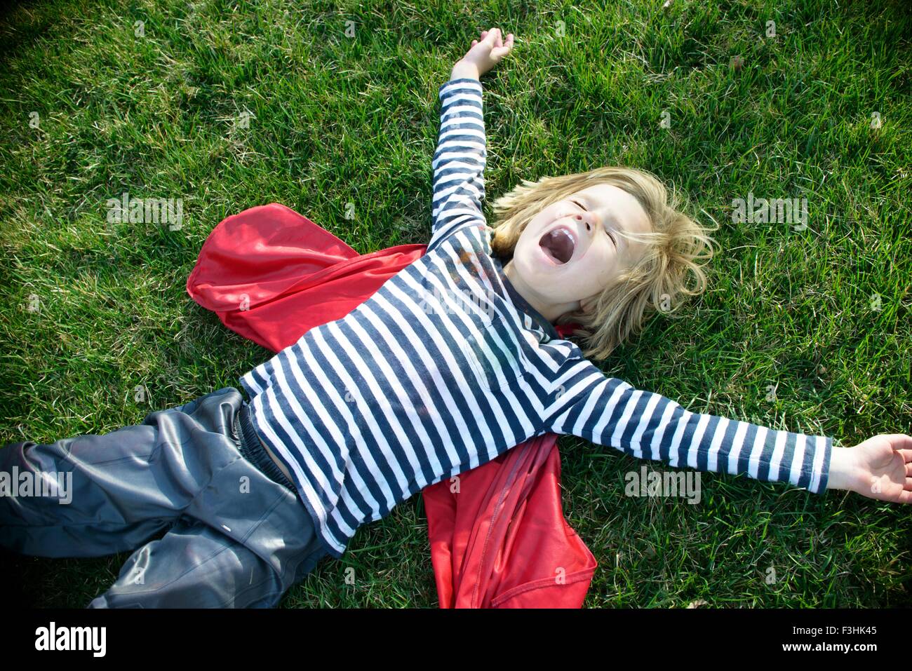Boy with red cape pretending to fly Stock Photo